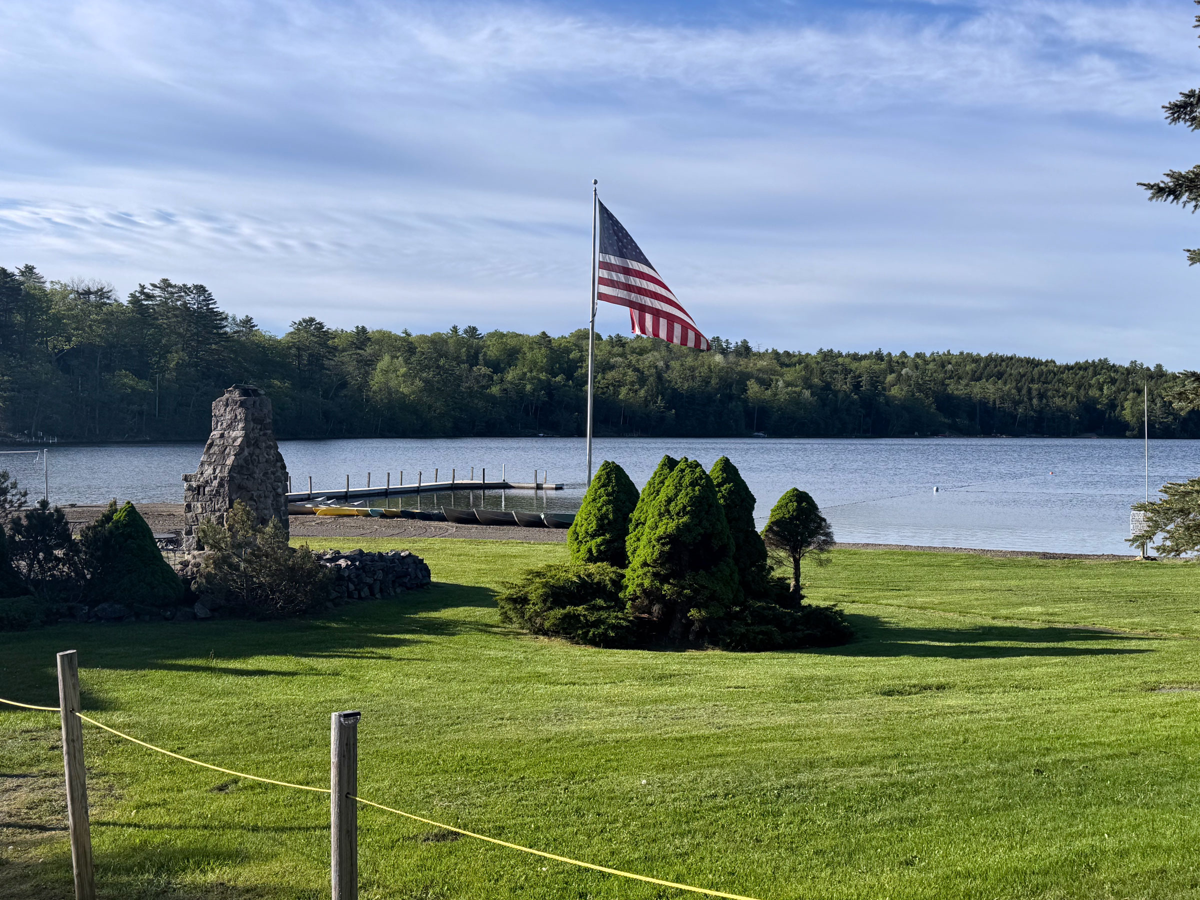 The lawn and sandy beach at Twin Pines Resort on Trout Lake, with the boat dock and wooded shoreline